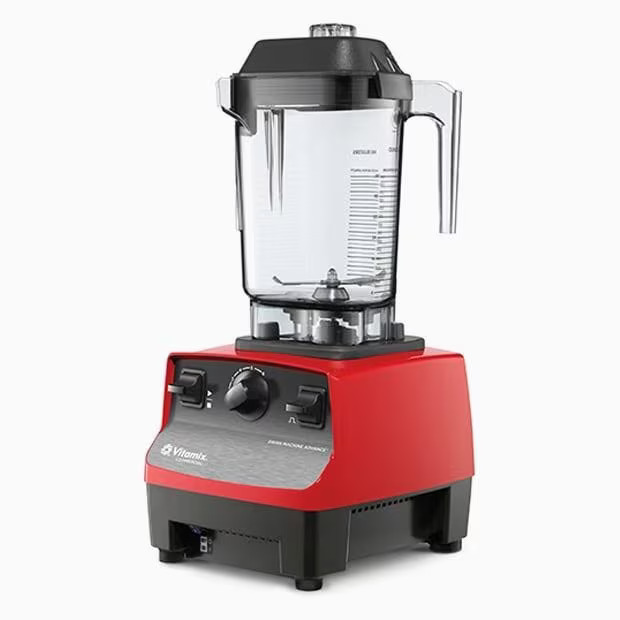 Un blender Vitamix roșu cu un ulcior din plastic transparent, capac negru și butoane de control pe partea din față, pe un fundal alb.